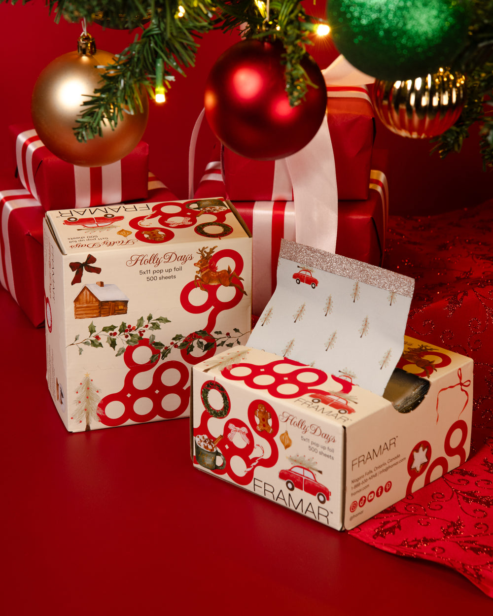 Holly Days pop-up foil boxes printed with a red vintage truck and evergreen trees, among red-wrapped gifts and Christmas ornaments